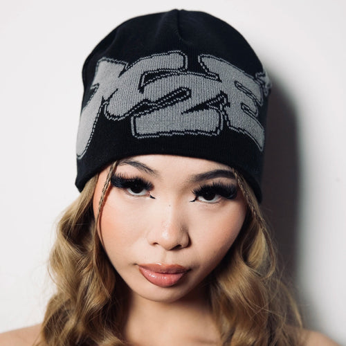 Woman wearing a black M2E beanie with a logo on a plain background