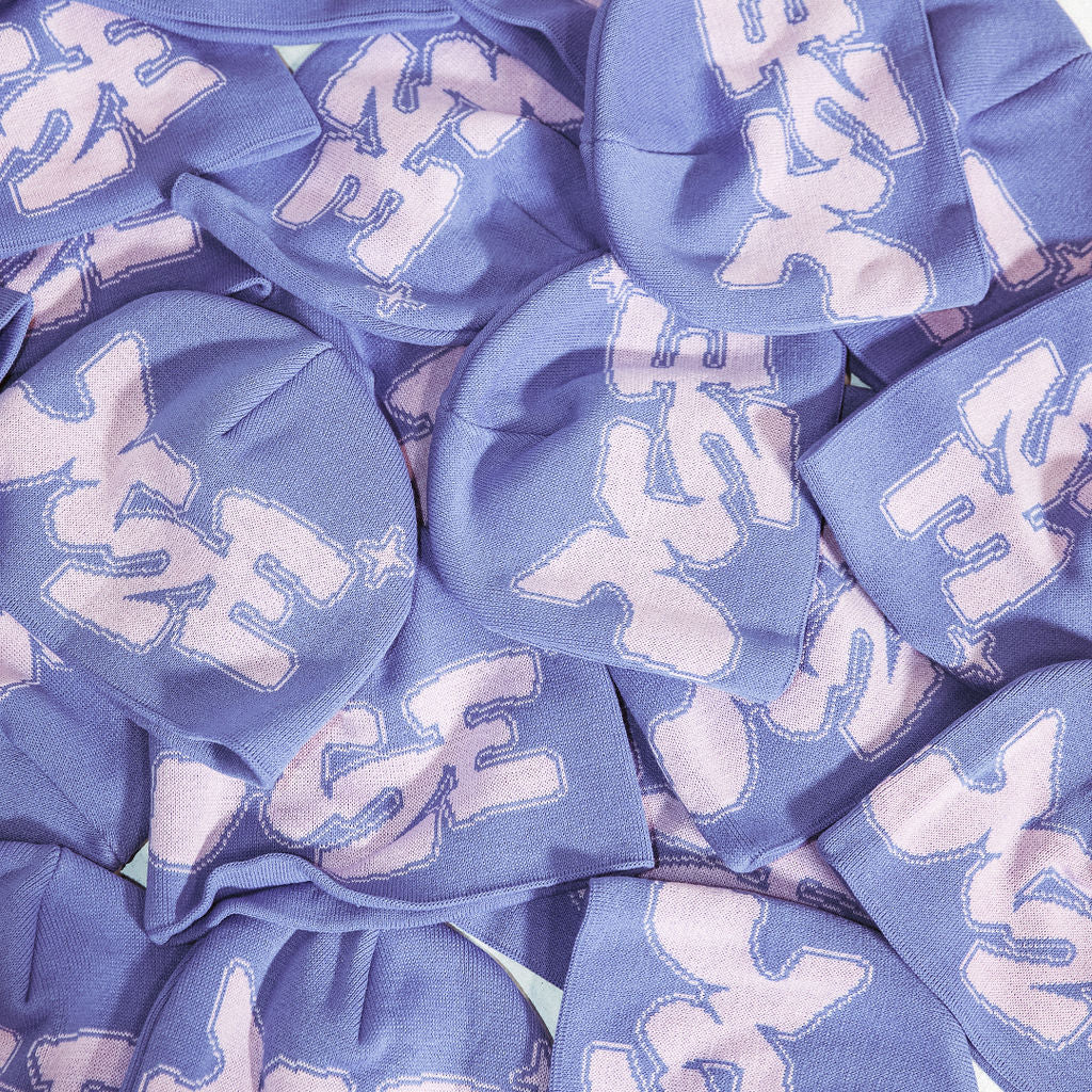 A pile of lilac M2E beanies stacked together