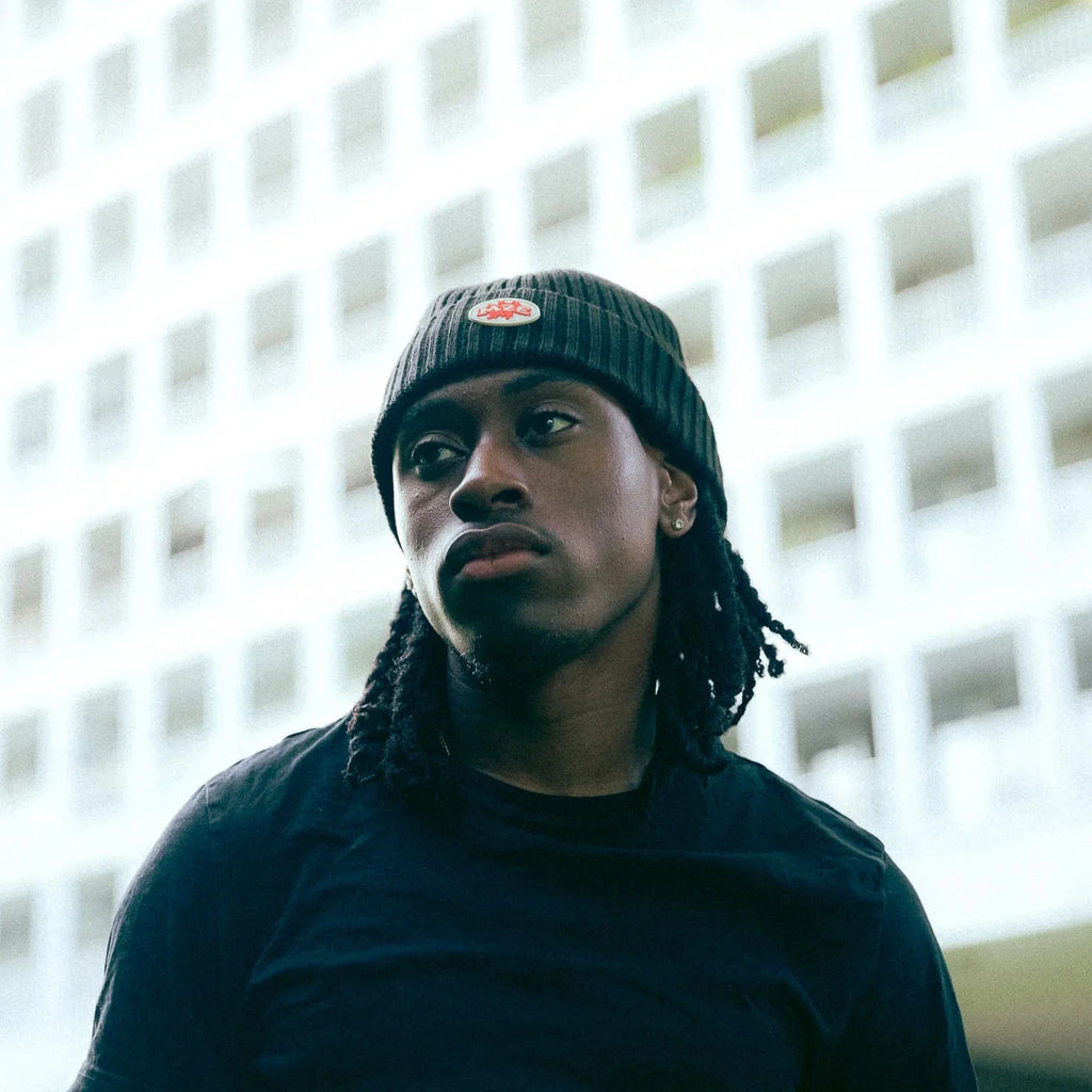 Person wearing a black M2E skully and dark clothing in front of a building with a grid pattern